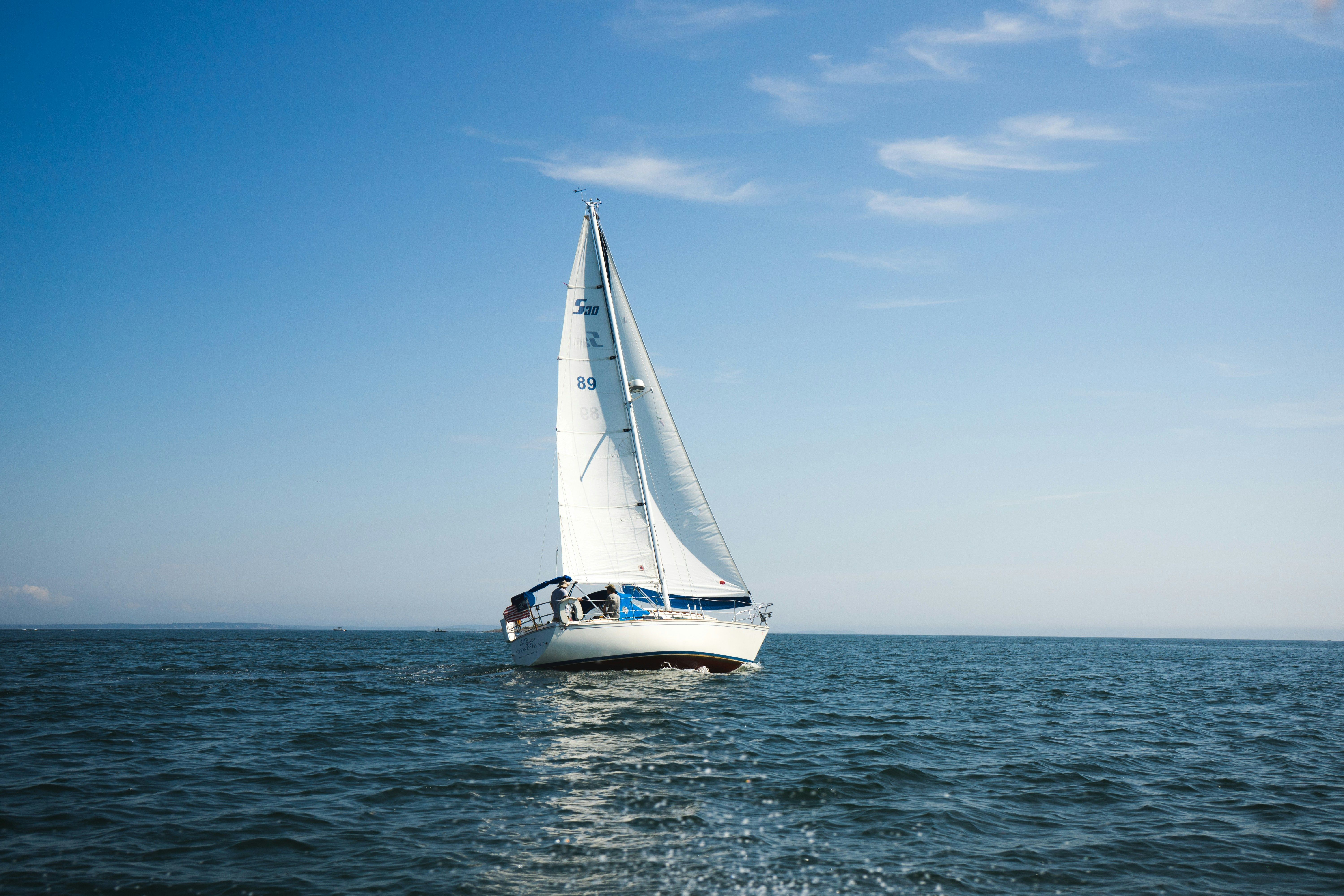 White sailboat with full sails cruising on calm blue Intracoastal water under a clear sky, evoking a Palm Beach County boating day.