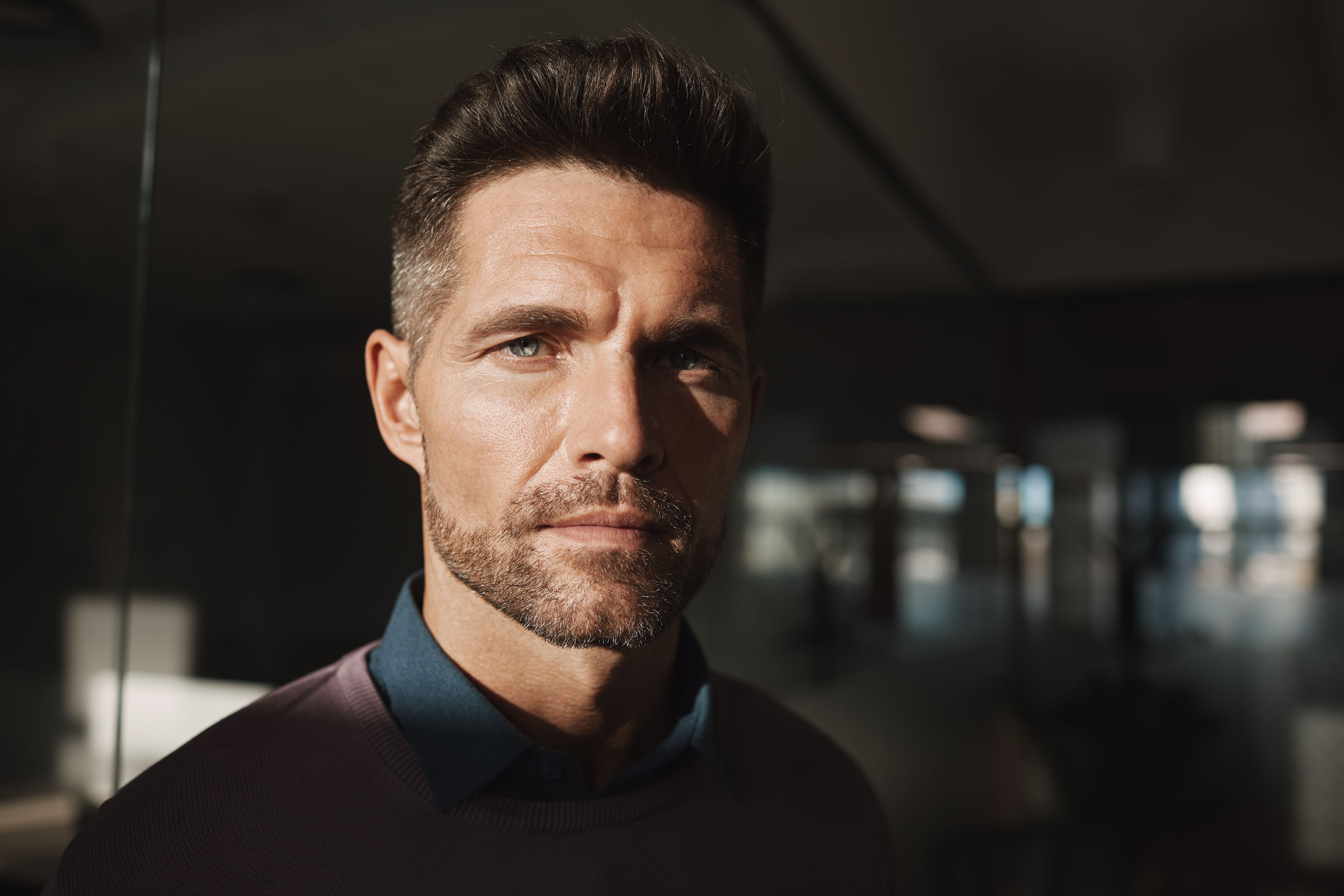 Serious man standing in a dimly lit office, reflecting the stress men face navigating mental health and the criminal justice system in Florida.