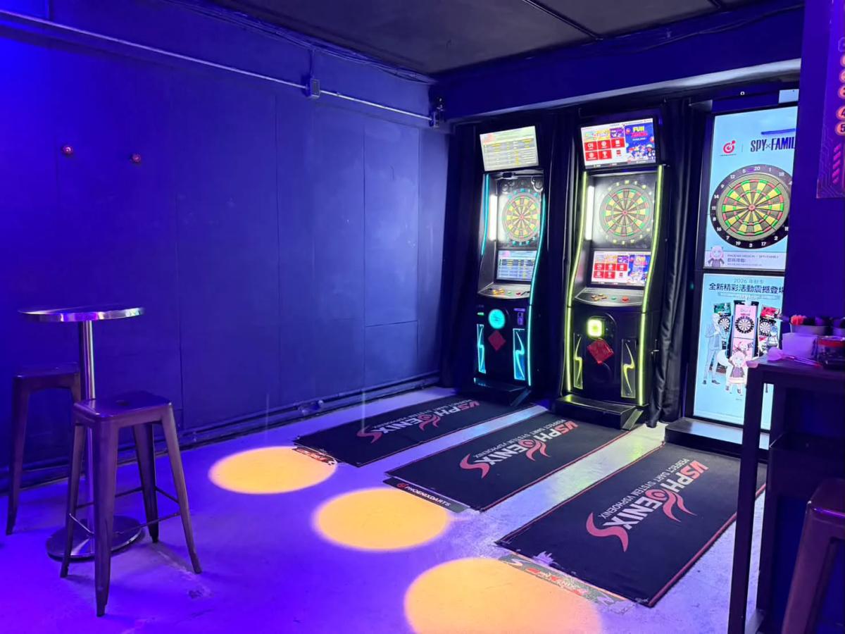 Inside AI DARTS, showing the self-service dart machines and seating along a quiet East District lane