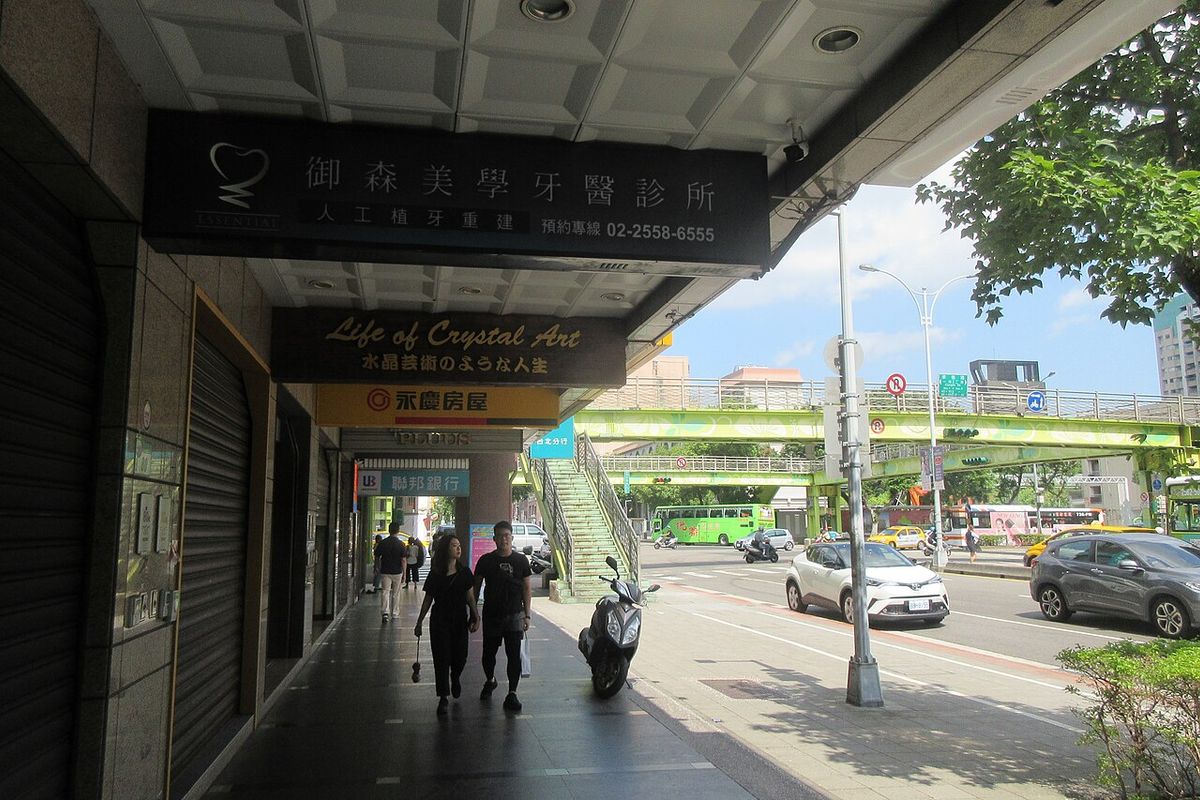 A covered arcade walkway on Nanjing West Road in Taipei, with a scooter parked at the edge