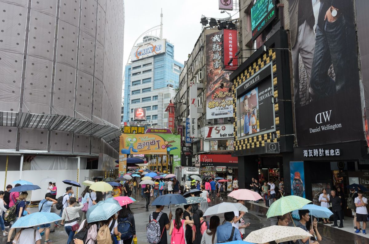 A crowd with umbrellas walking into Hanzhong Street in Ximending, Taipei, on a rainy June day