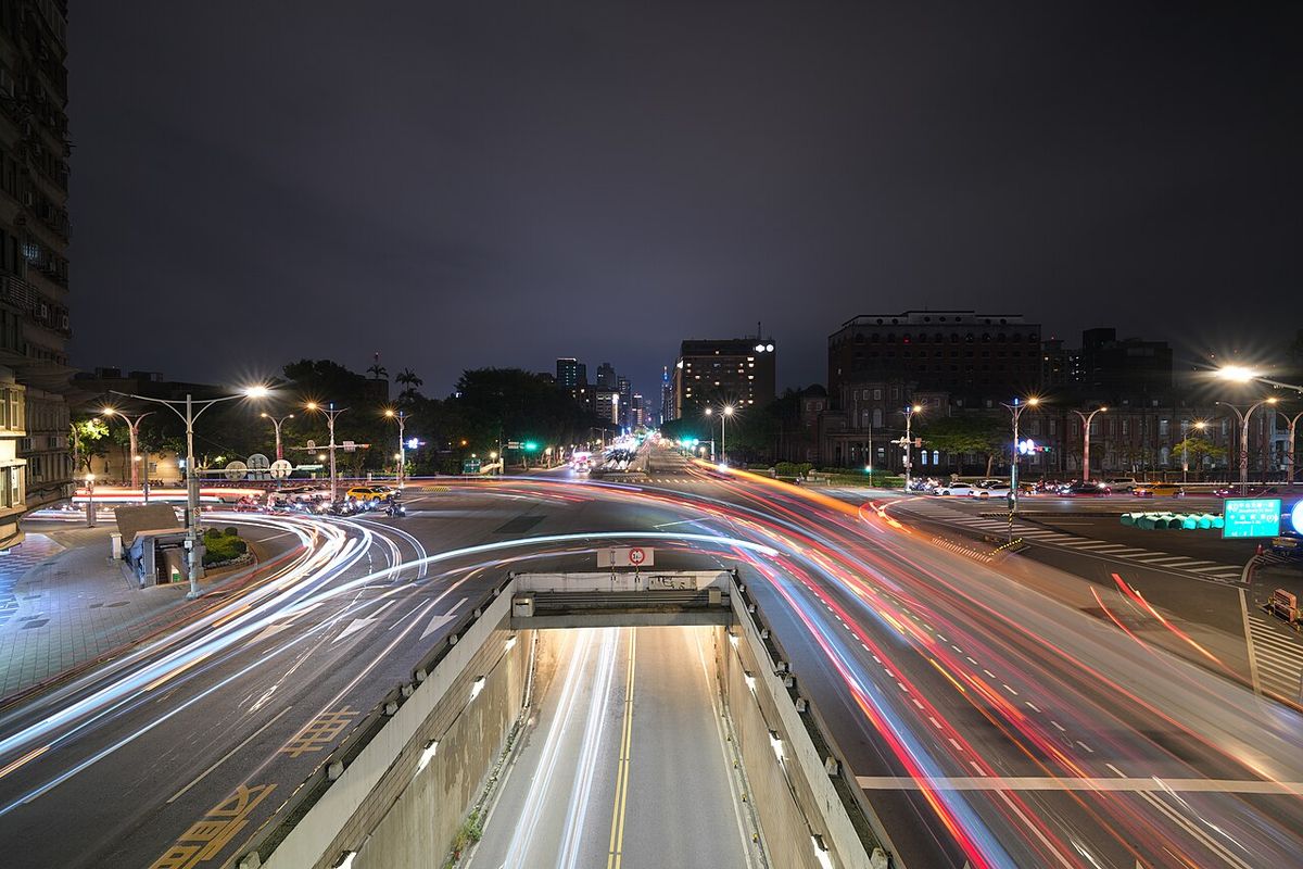 A busy Taipei intersection at night with light trails from passing traffic