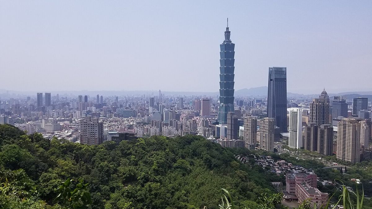 Taipei 101 and the Taipei skyline seen from a green hillside trail