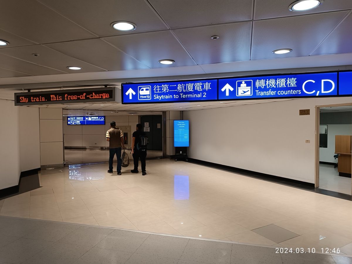 Arrivals area at Taoyuan International Airport with bilingual signs for the Skytrain and transfer counters