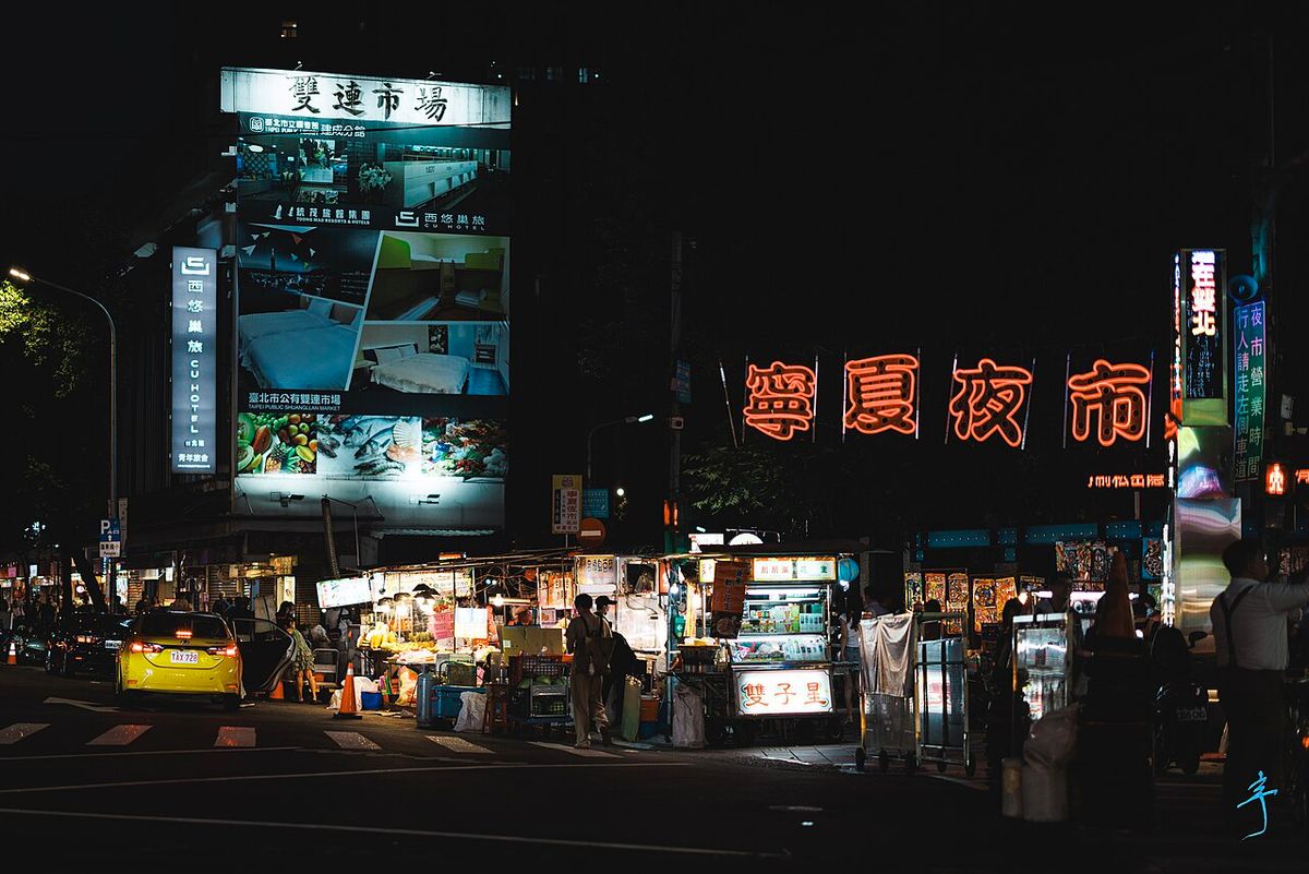 Ningxia Night Market at night with food stalls and the glowing market sign