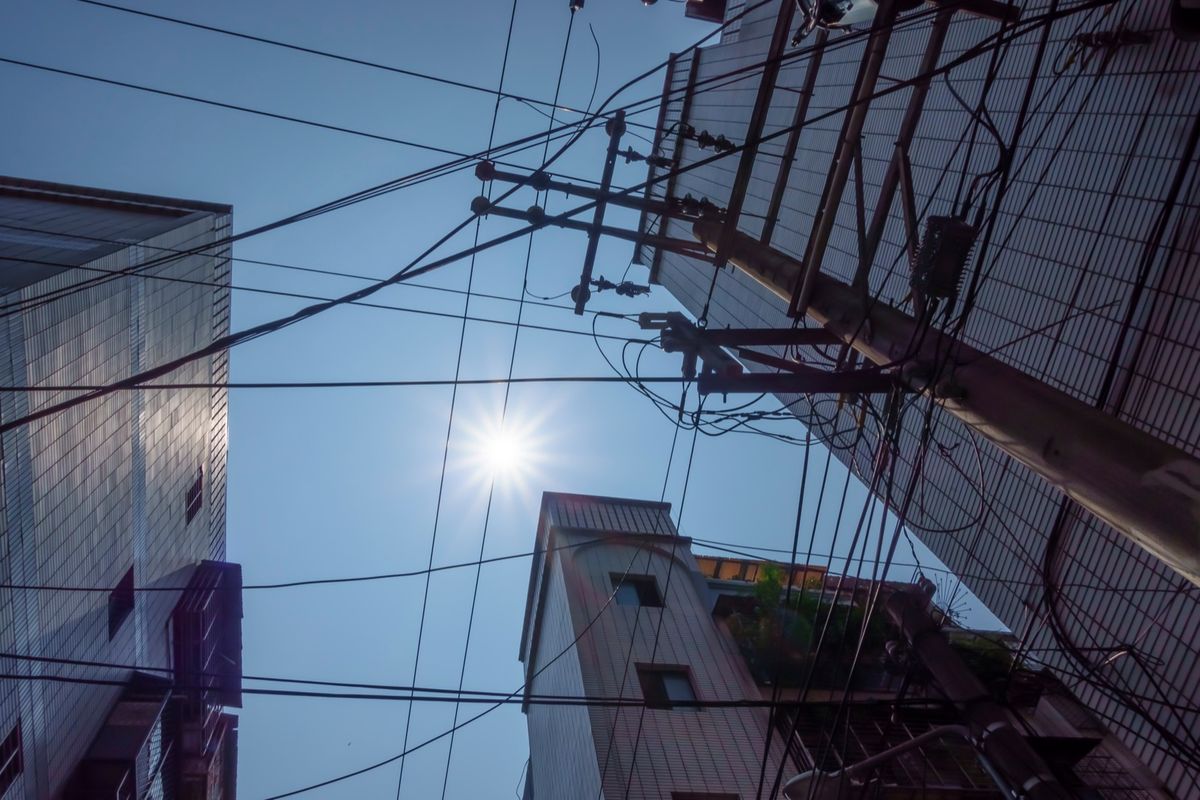 Three older apartment buildings and a utility pole seen from below on a sunny day in Taipei