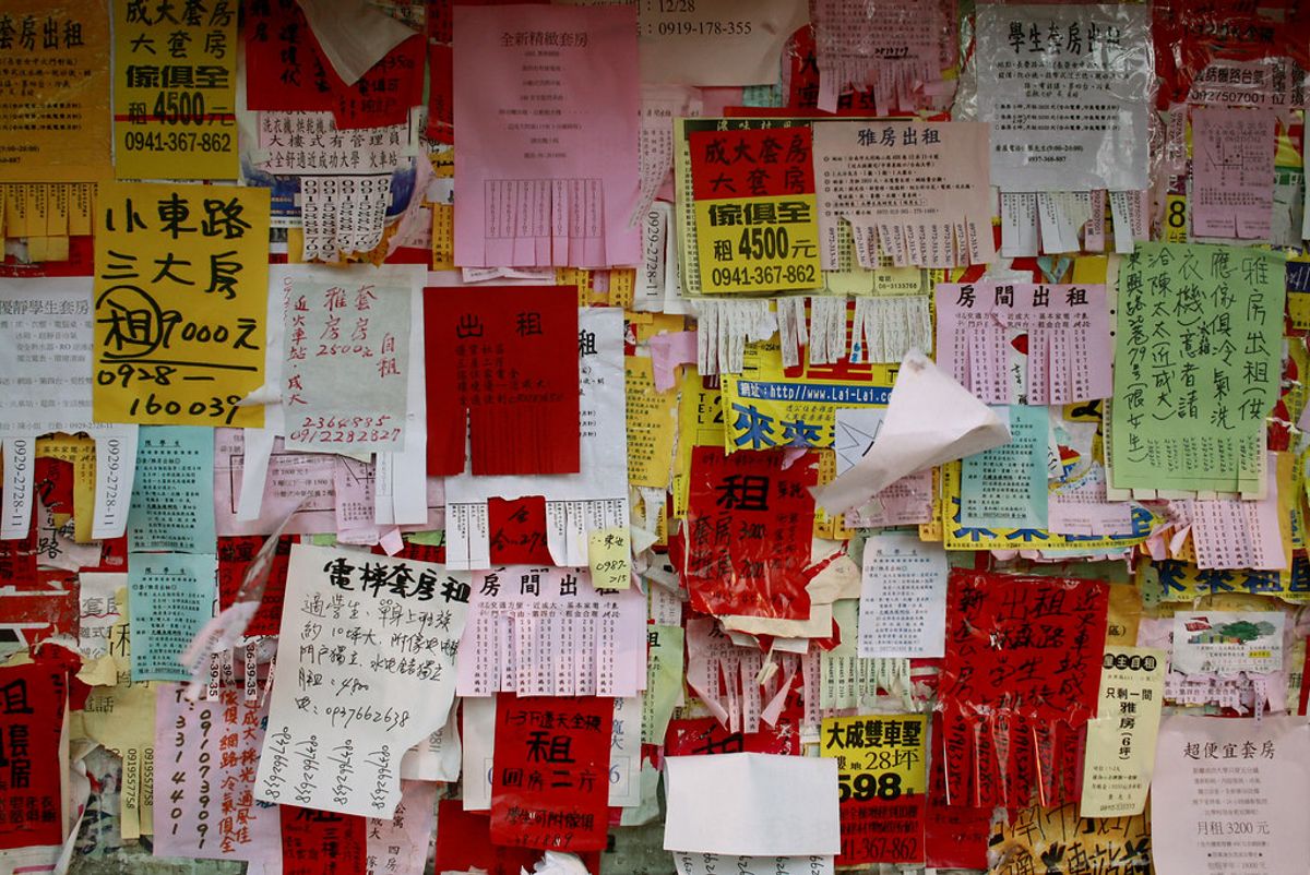A wall covered in handwritten rental flyers for rooms and suites in Taiwan