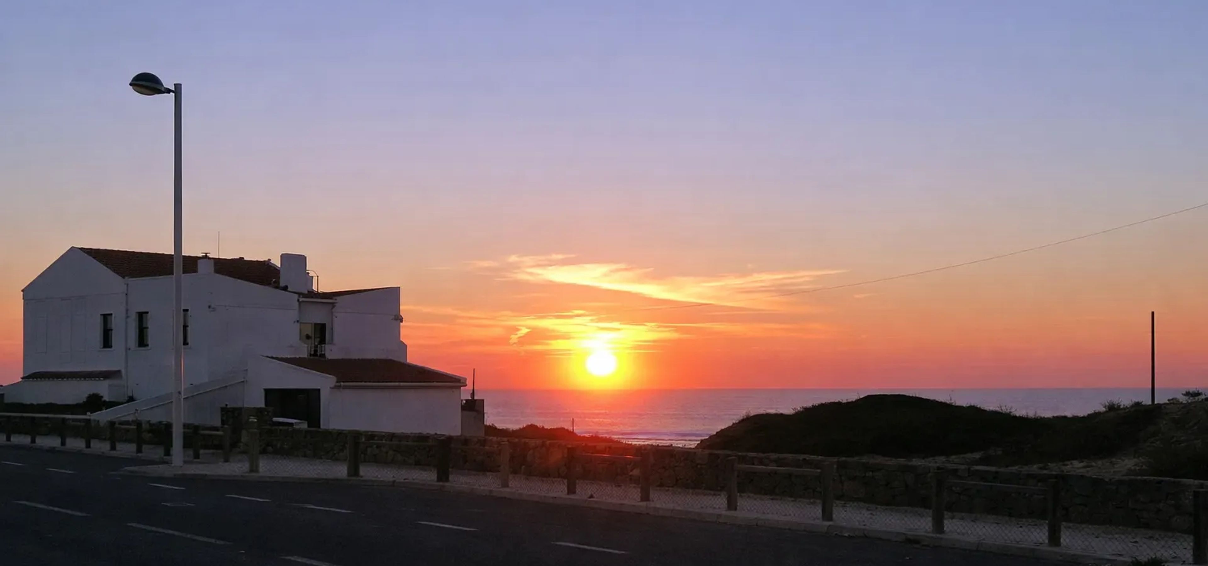 Leuchtturm von Vila Nova de Milfontes bei Sonnenuntergang über dem Meer