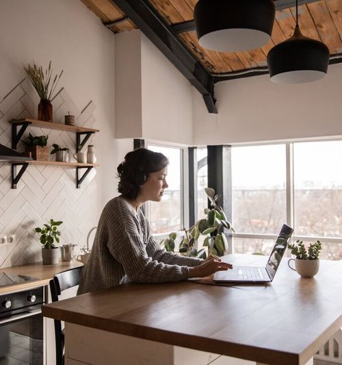 Image of a woman seated at a kitchen island, working on a laptop