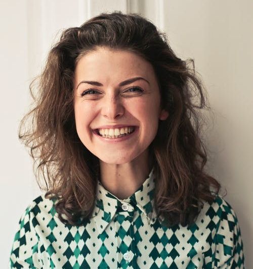 Image of a woman standing against a neutral backdrop, smiling at the camera