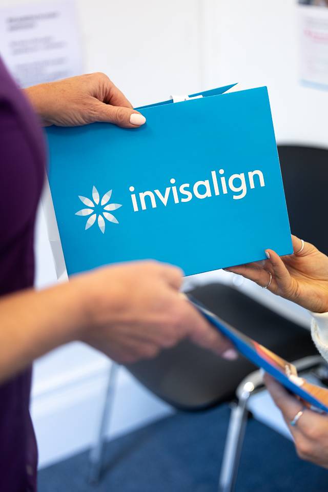 Nurse handing a blue Invisalign bag to a patient