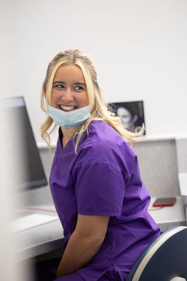 Receptionist facing to left on the phone smiling at patient