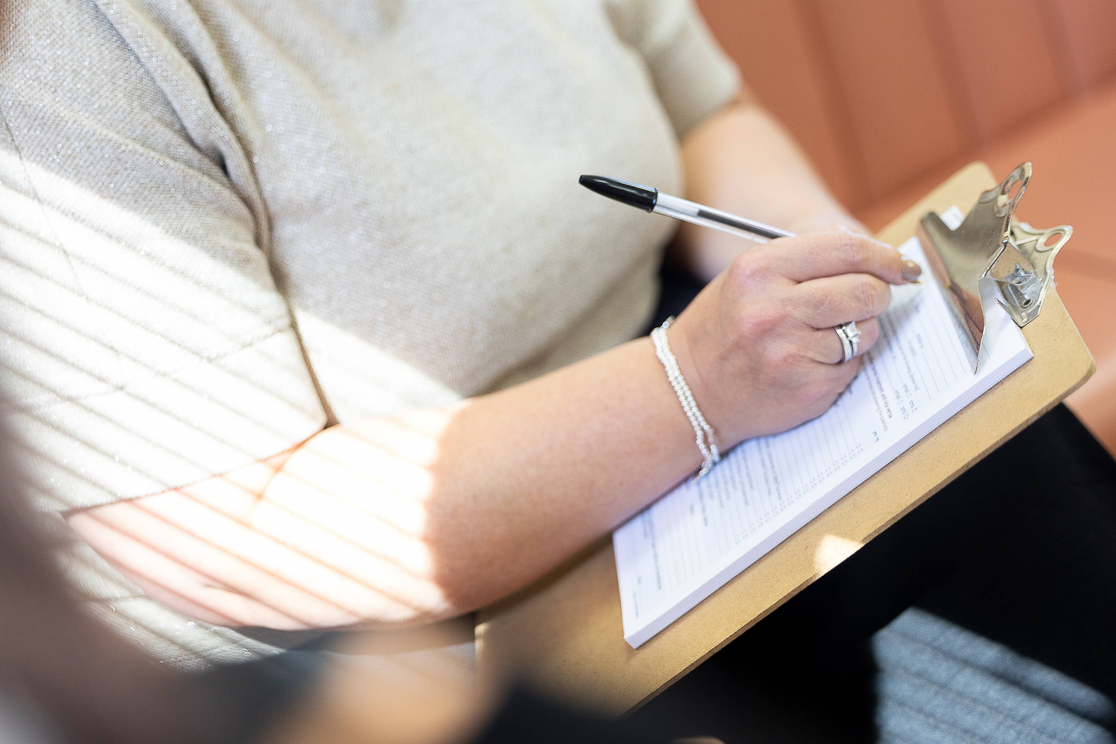 A patient filling out a membership registration form on a clipboard with a pen