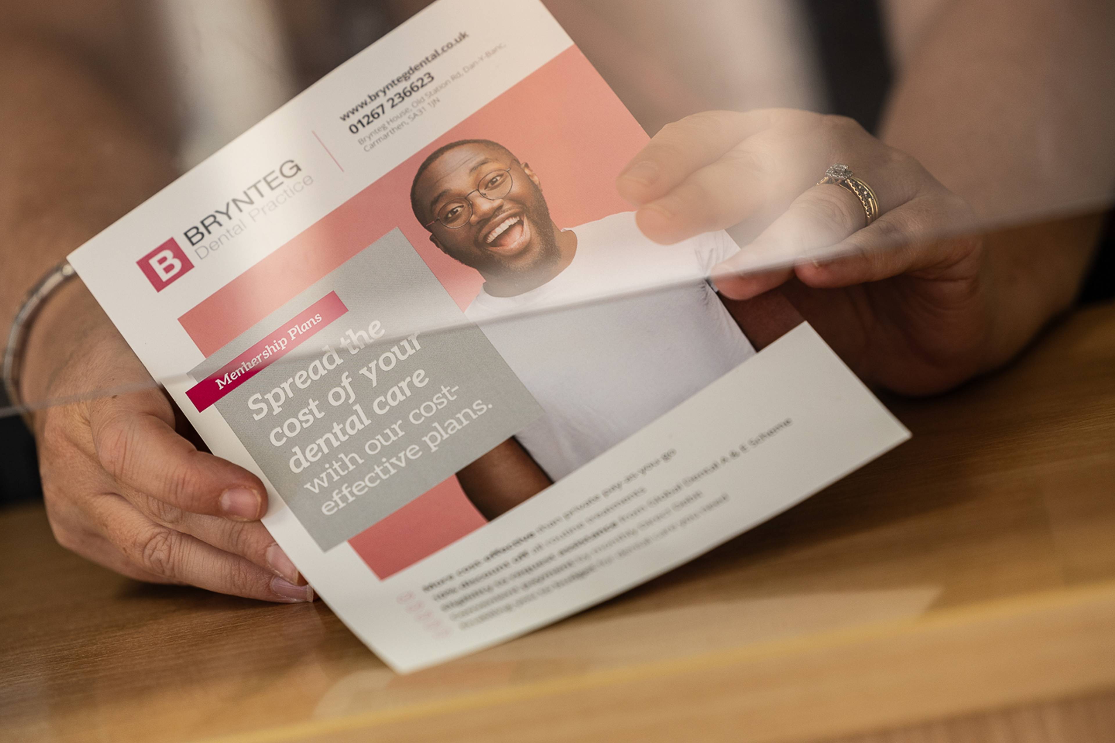 Close of up receptionist's hands holding a membership plan leaftlet