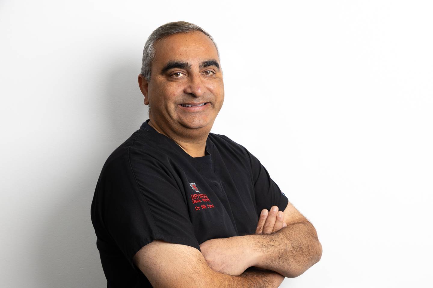 Pen y deintydd Nik Patel yn gwenu