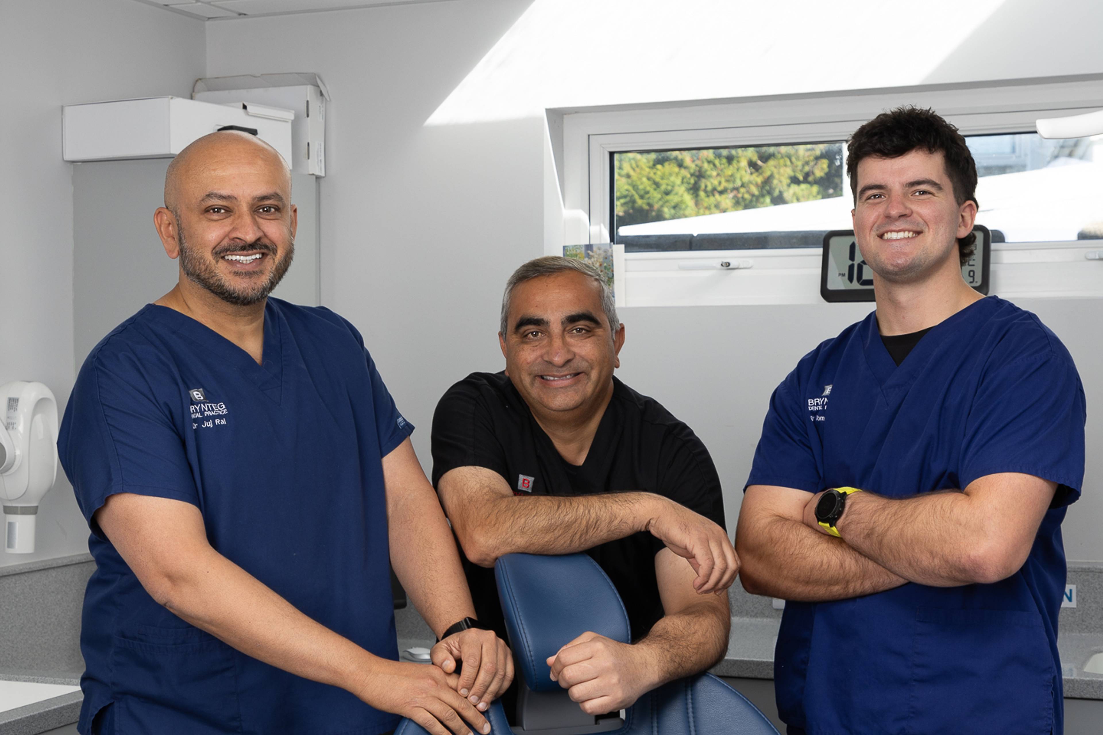 Safodd tri deintydd gyda'i gilydd mewn llawdriniaeth wyn a llwyd yn gwenu ar y camera