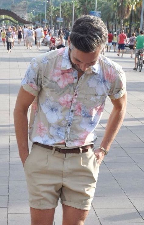 Hombre con camisa floreada y shorts, con colores arena