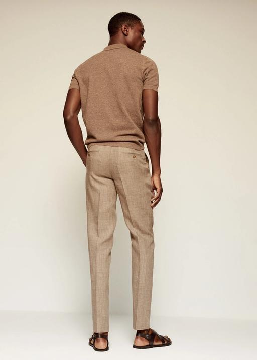 Hombre de espaldas vestido con camisa polo café y pantalón de lino del mismo color con un tono más bajo.