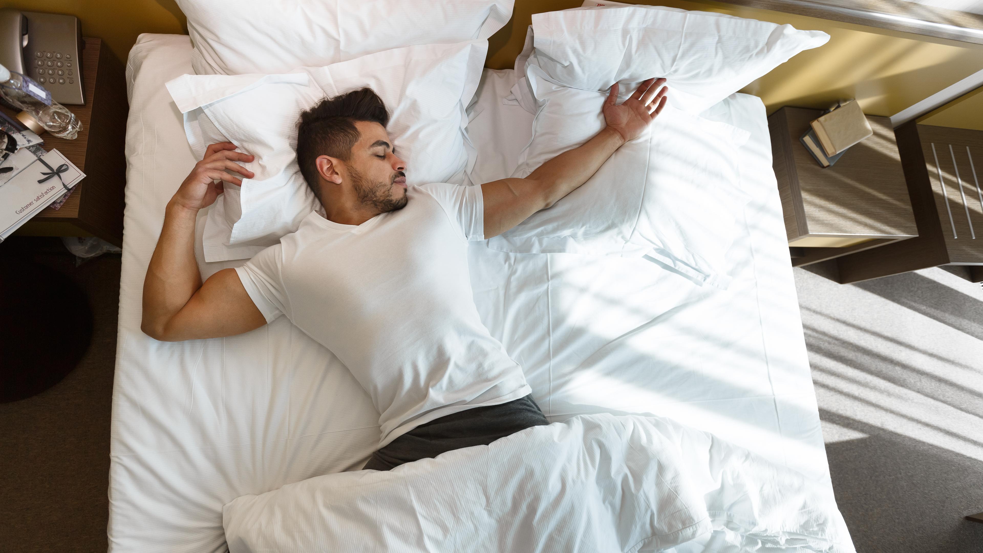man sleeping on bed using habits to prevent hair loss 
