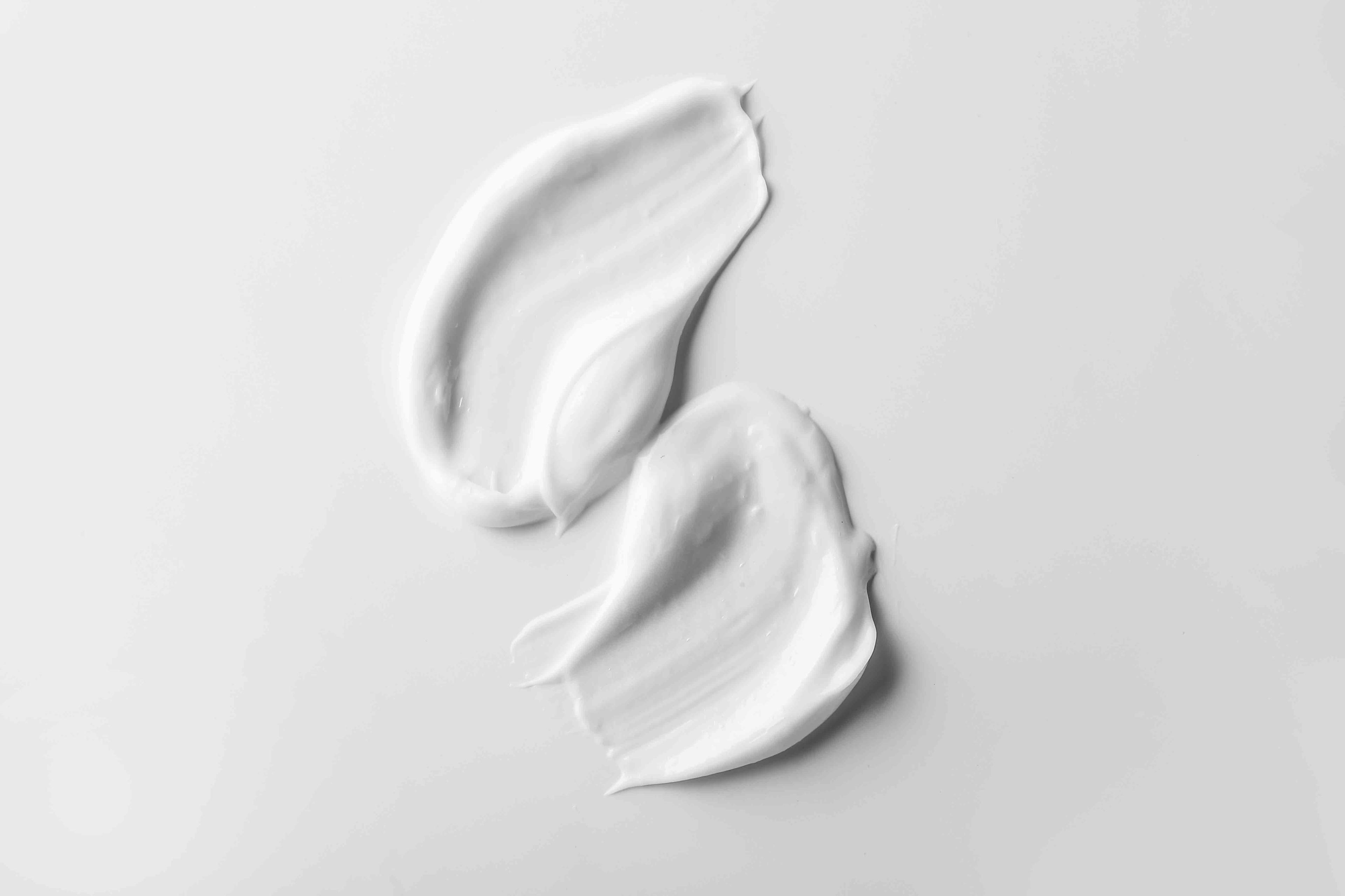 Two smears of white cream on a white background.