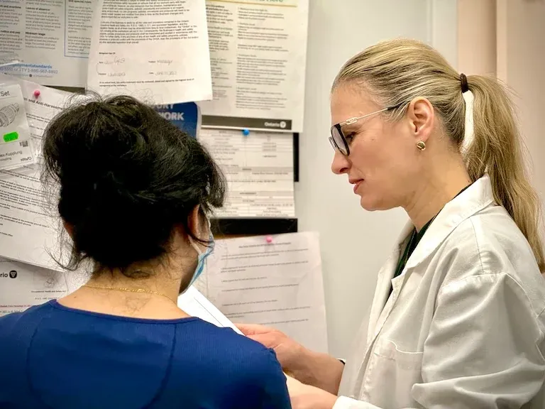 Dr.Alena is reading documents in the office with a dental assistant