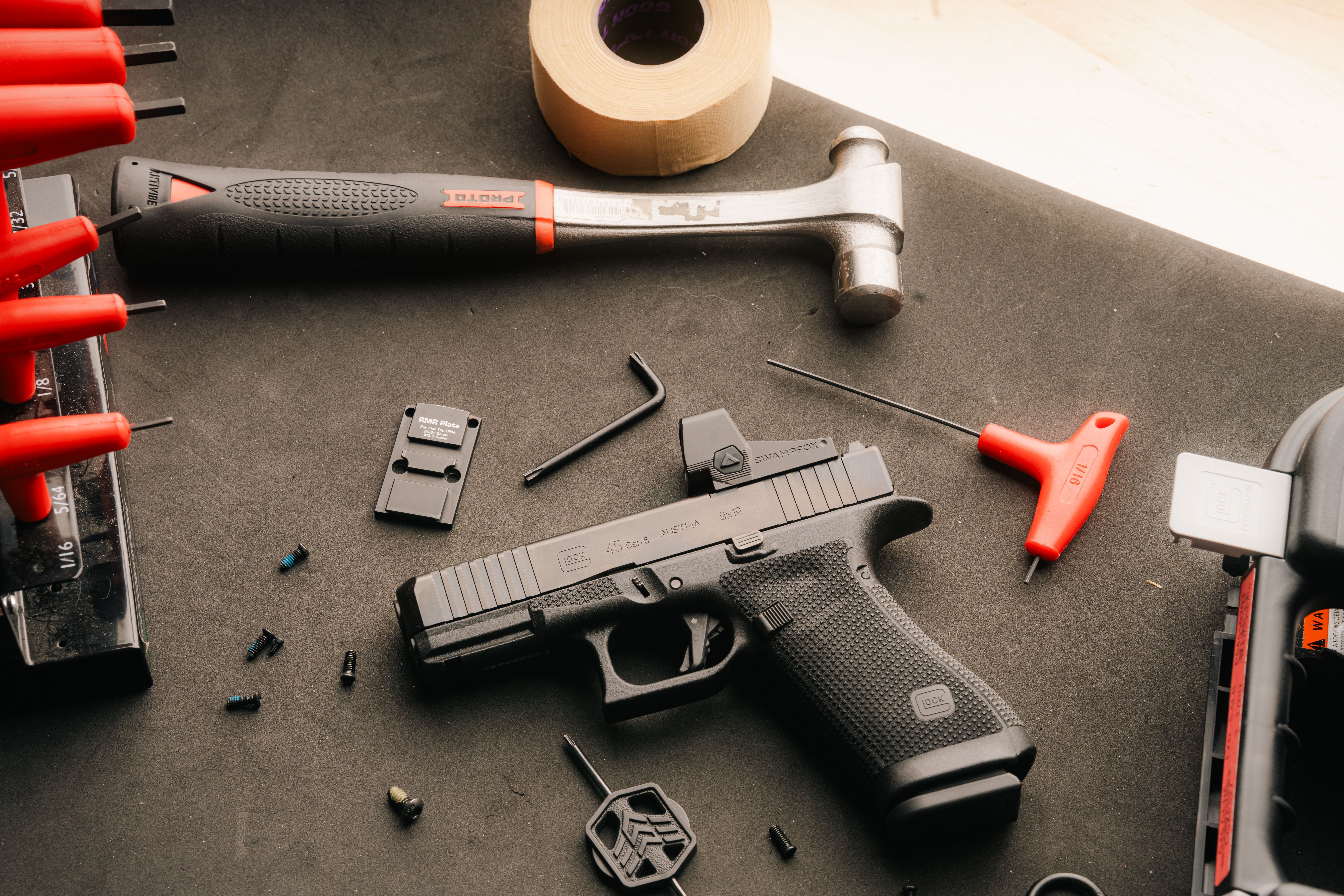 Flatlay of a double stack Glock with a red dot optic on a table