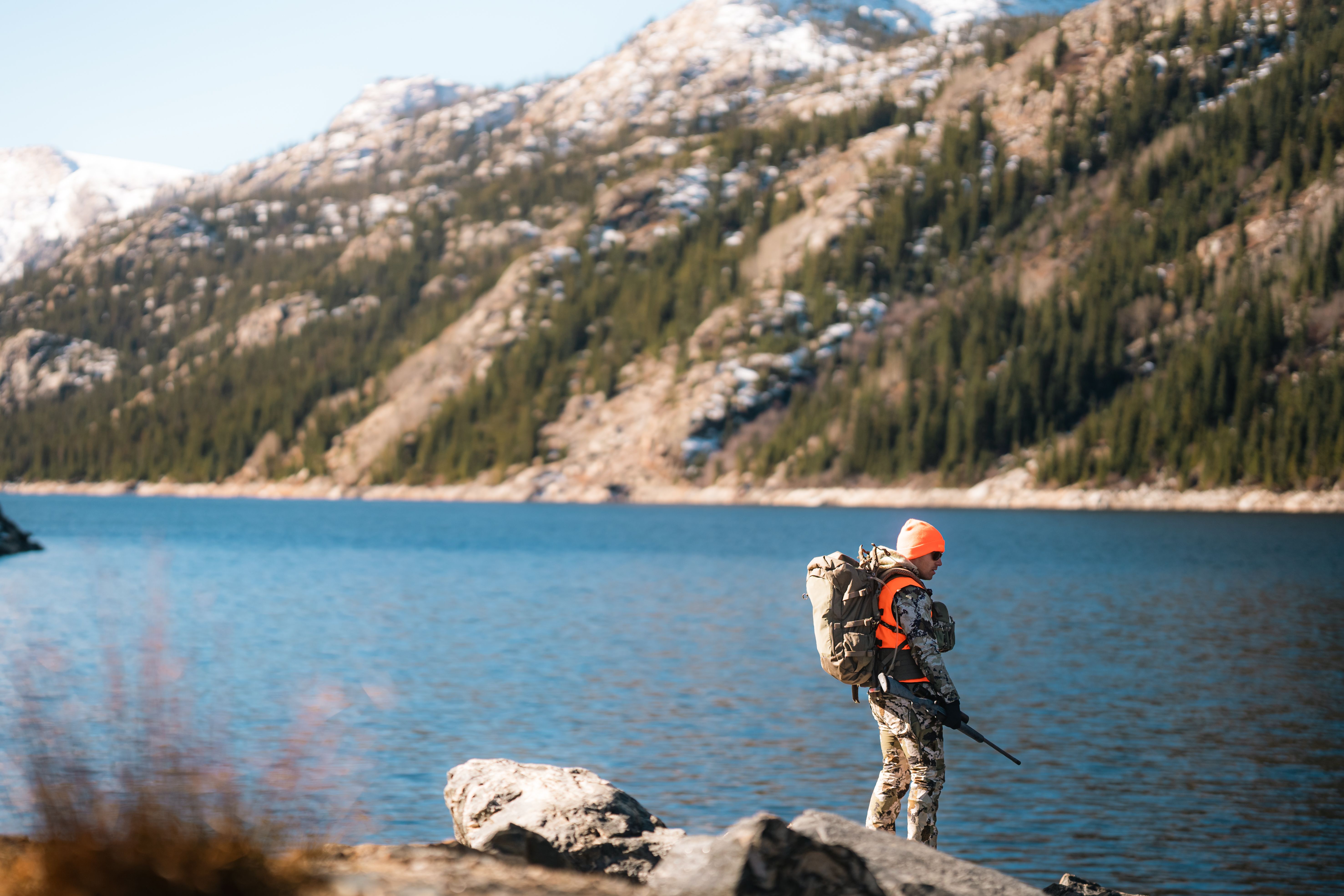 Shooter aiming rifle with optic at an outdoor range
