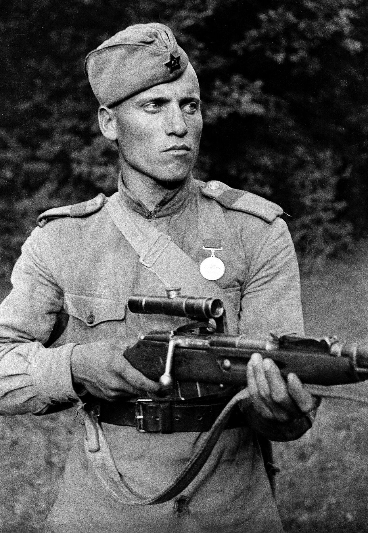 Soviet sniper with PU scope on Mosin-Nagant 91/30 — the side-rail mount kept the receiver clear for stripper-clip reloads and preserved access to iron sights
