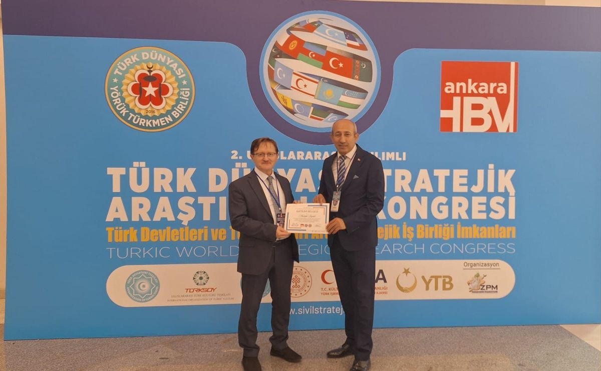 Mustafa Bıyıklı, kongre panosunun önünde katılım belgesini alırken