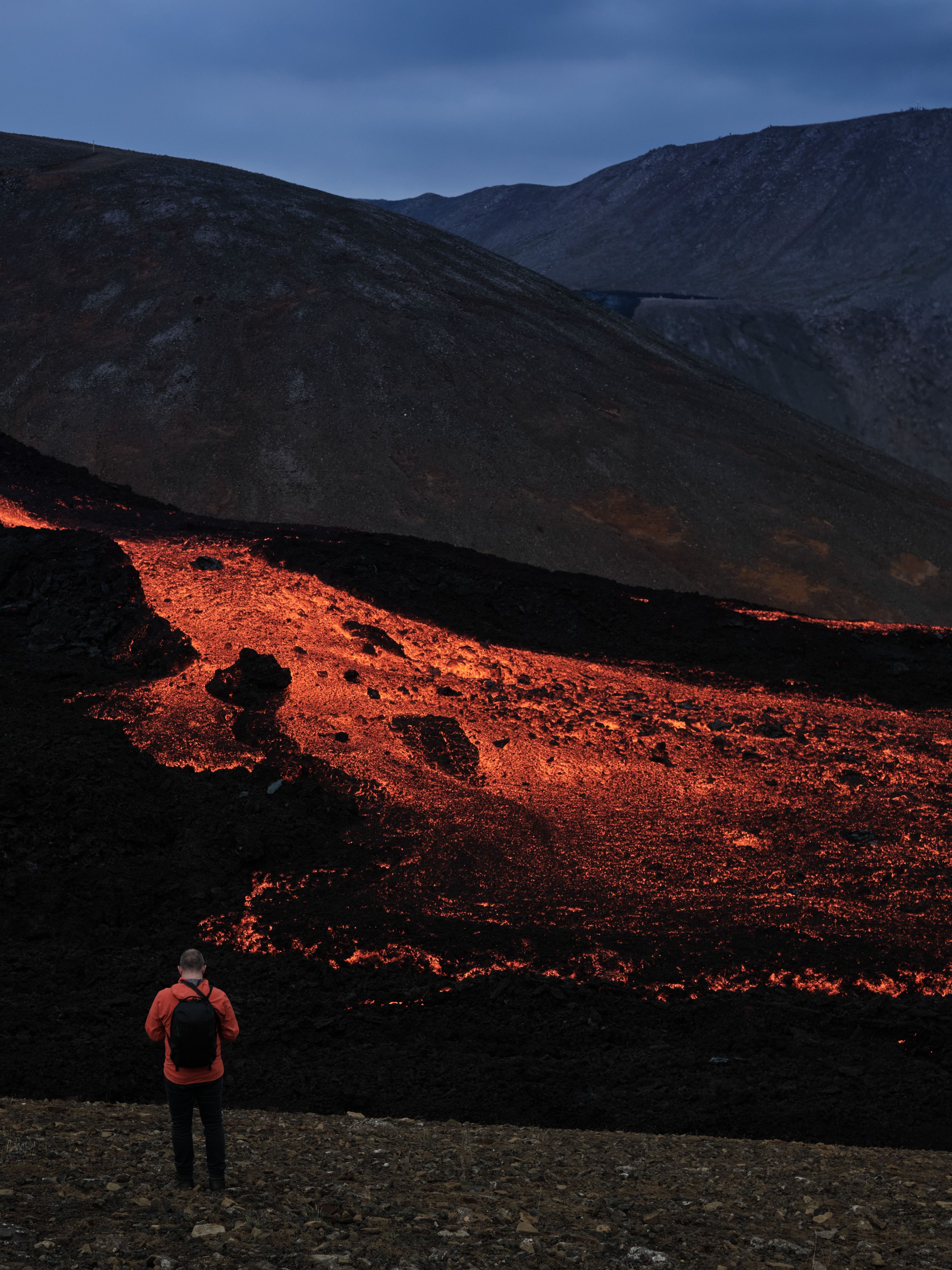 A man in an orange jacket by the lava