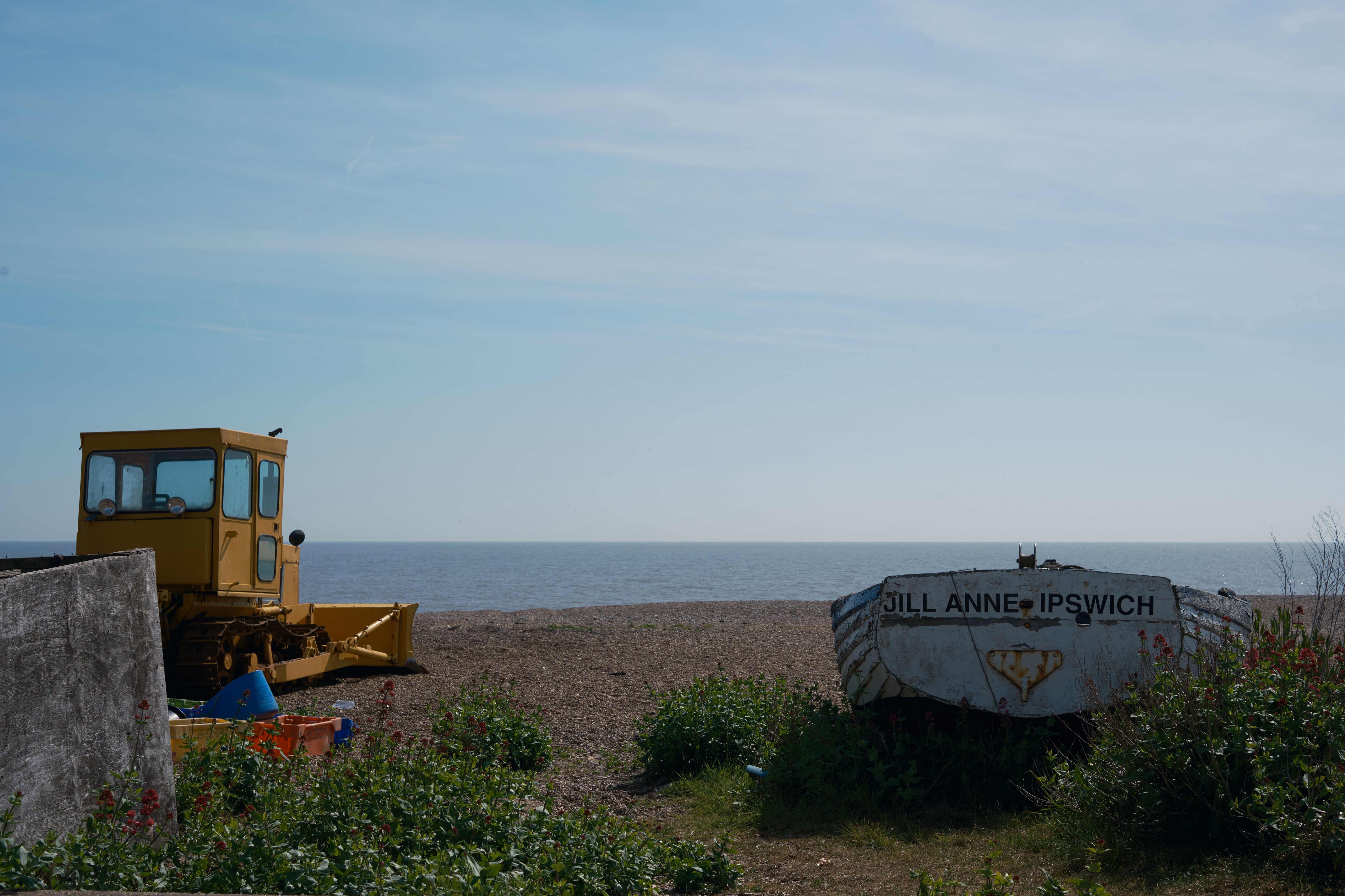A digger and boat among the weed and pebbles