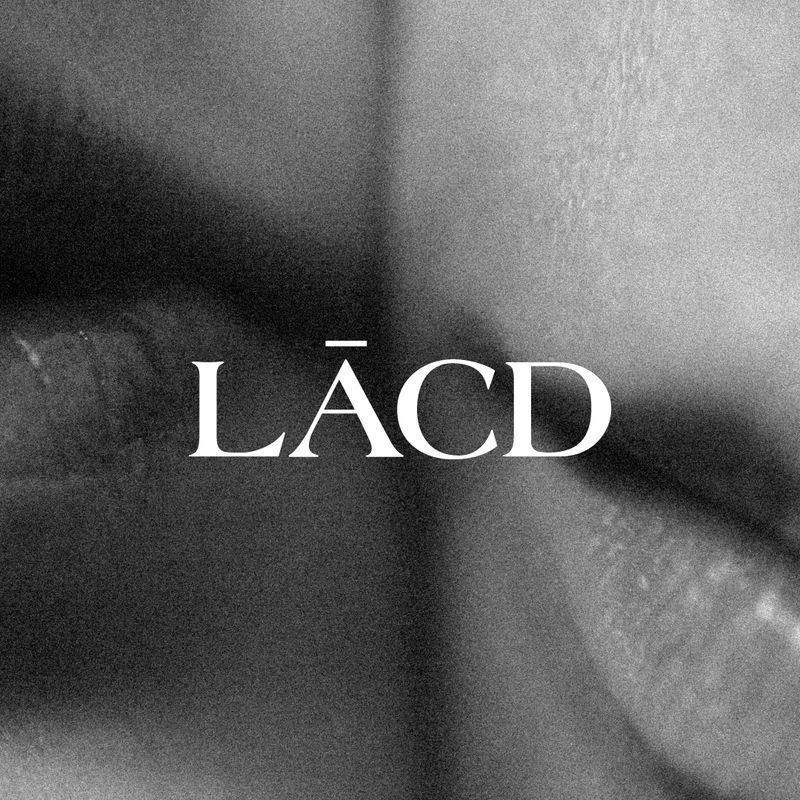 White text saying LĀCD placed over a black and white background image of two women's lips