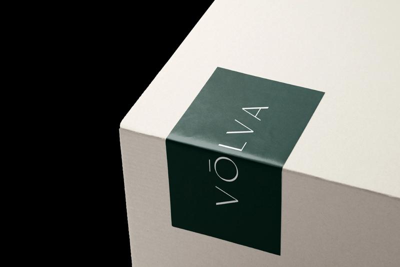 Emerald green business card with white type saying Vōlva on a cream marble background.