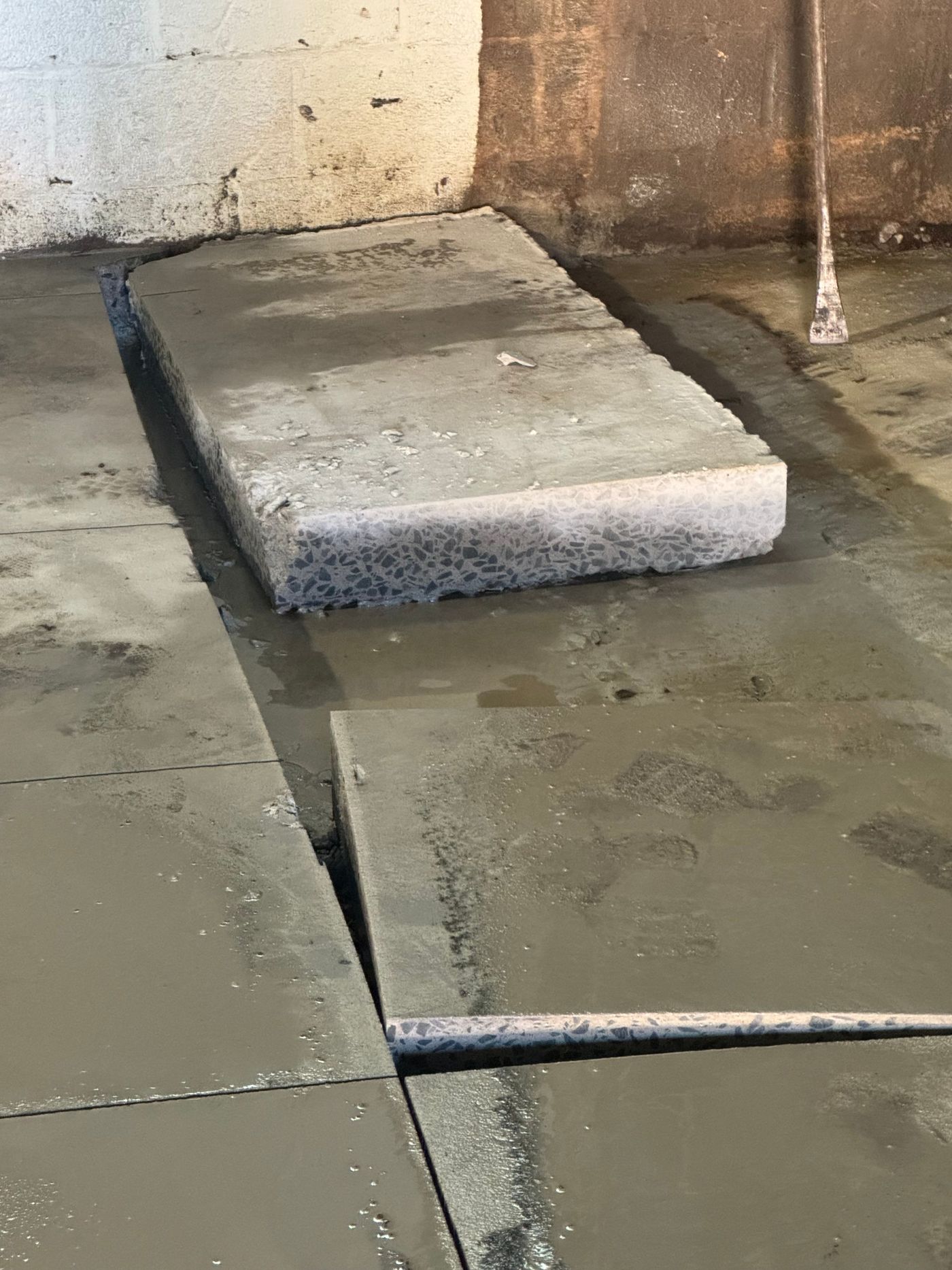 Concrete floor cut into rectangular sections at 280 Blake Street, with one thick slab raised above the surrounding floor.