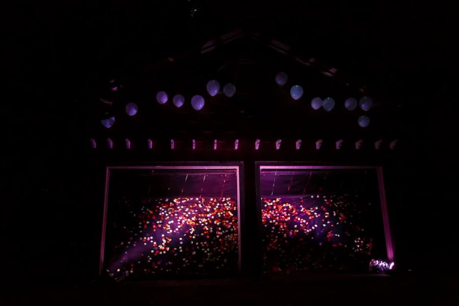A dark Garage #4 scene from Boitatá with glowing purple light, balloons, and hundreds of small colored eye shapes across the set.