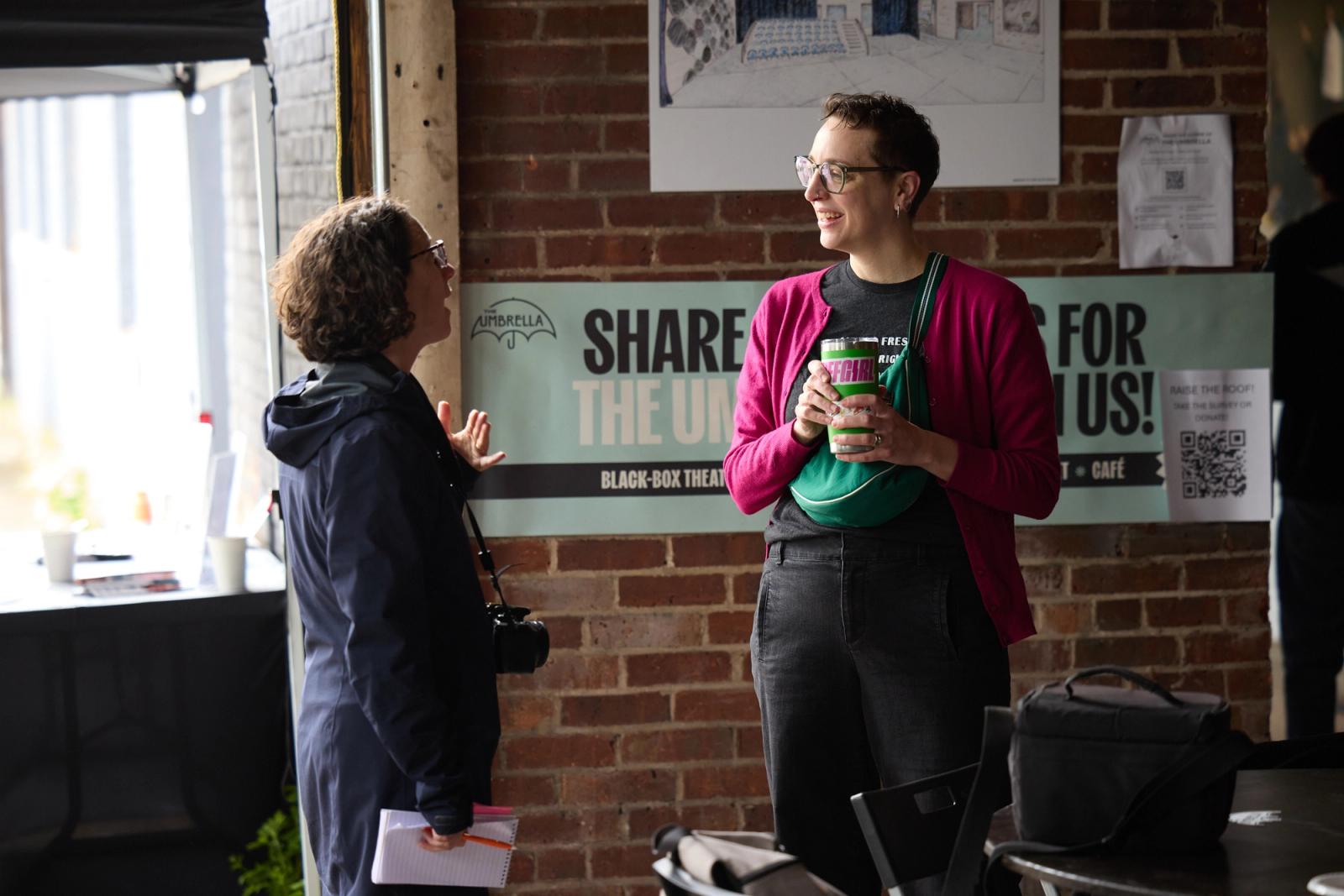 Open-house conversation in The Umbrella space with people gathered around the table.