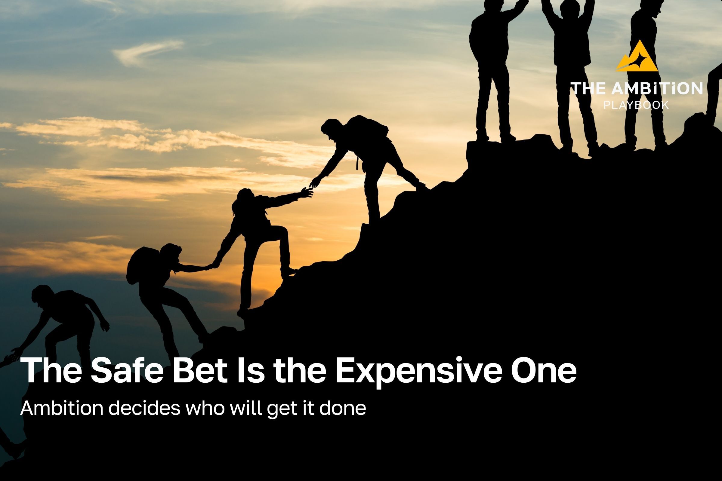 A team of people helping one another scale the summit of a mountain with a sunset behind them