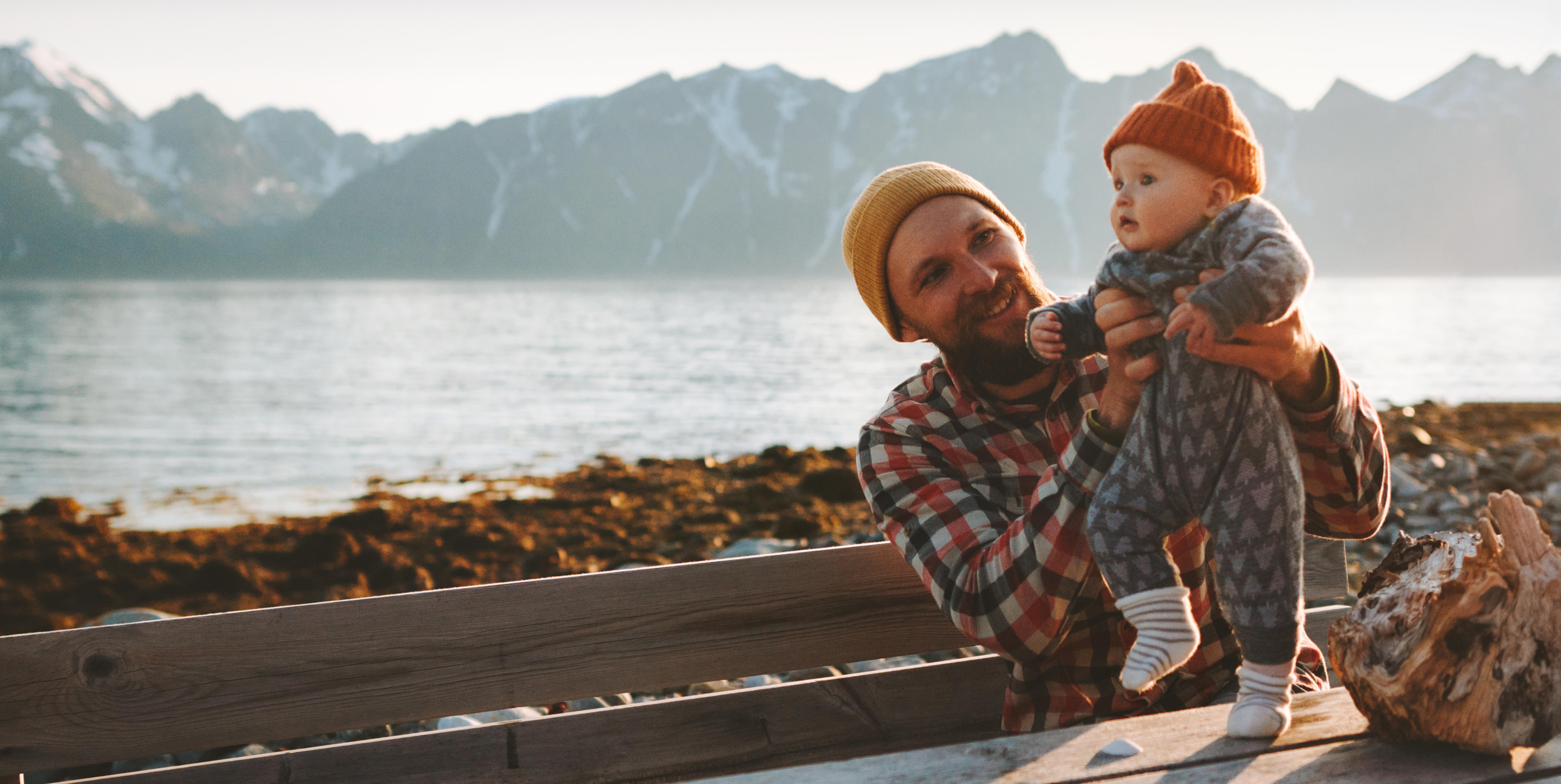 Man holding his infant whilst practicing walking on a tabletop