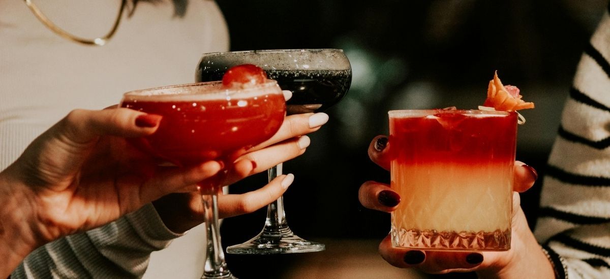 cocktails in the hands of patrons at the bar