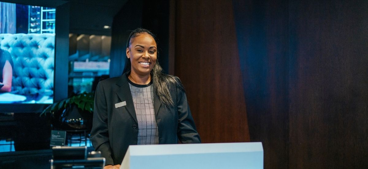 hospitality employee using technology interface to greet guests at a hotel
