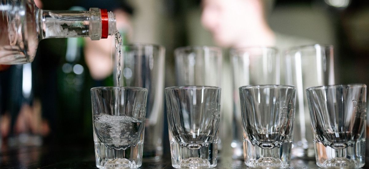vodka being poured into shot glasses on the bar