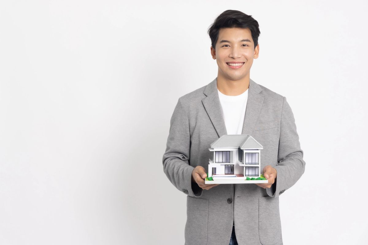 Asian male from property management agency in the Philippines holds a miniature house