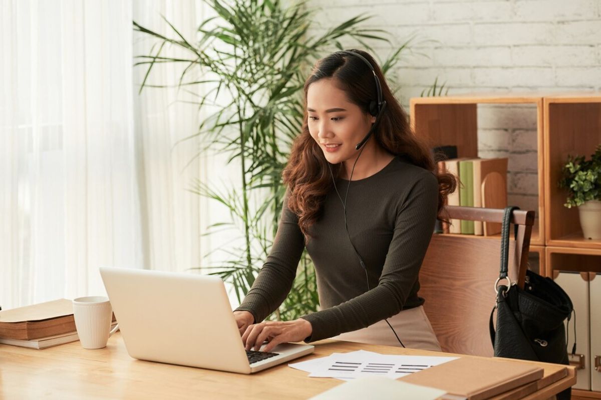 woman wearing headset using laptop