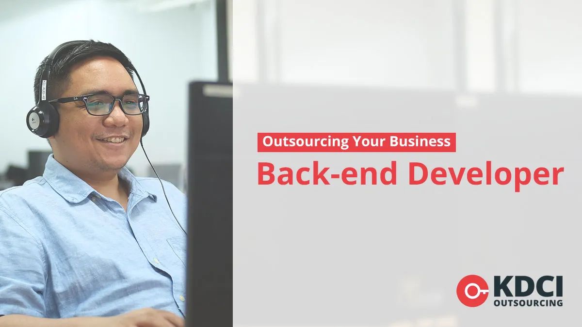 A smiling male back-end developer wearing headset and working on PC