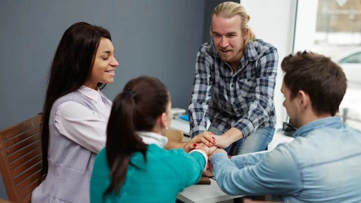 four people hands together while huddling