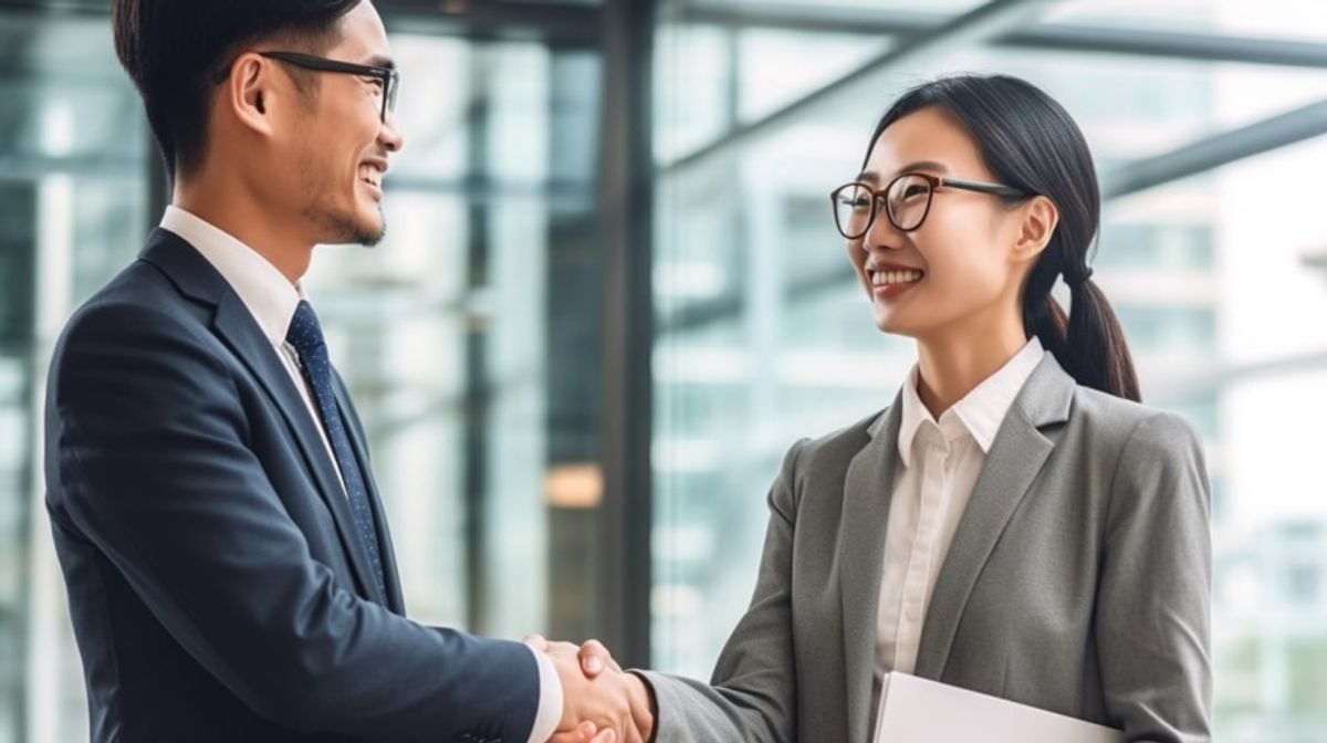 In the heart of the office, an Asian boss and his newly hired data entry specialist is beaming with joy, engaging in a warm handshake following a successful hiring process. Their smiles radiate satisfaction, indicating the beginning of a fruitful professional journey together.