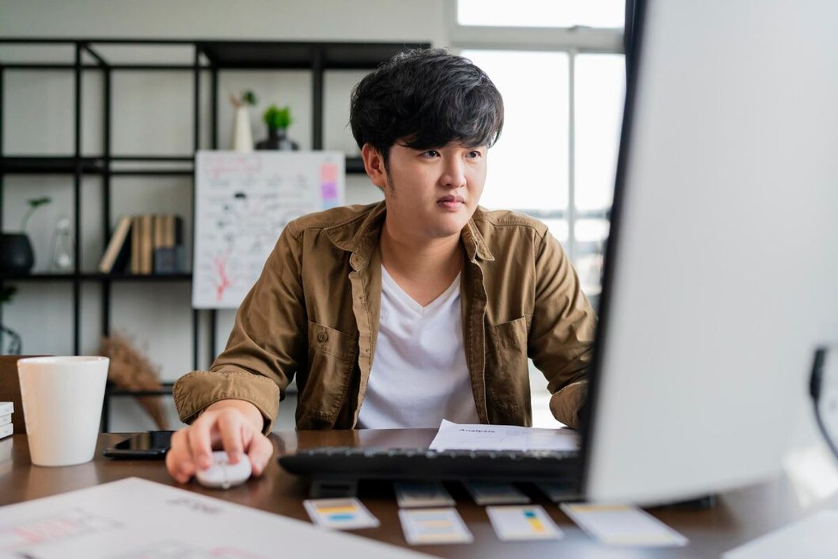man with brown shirt on a computer
