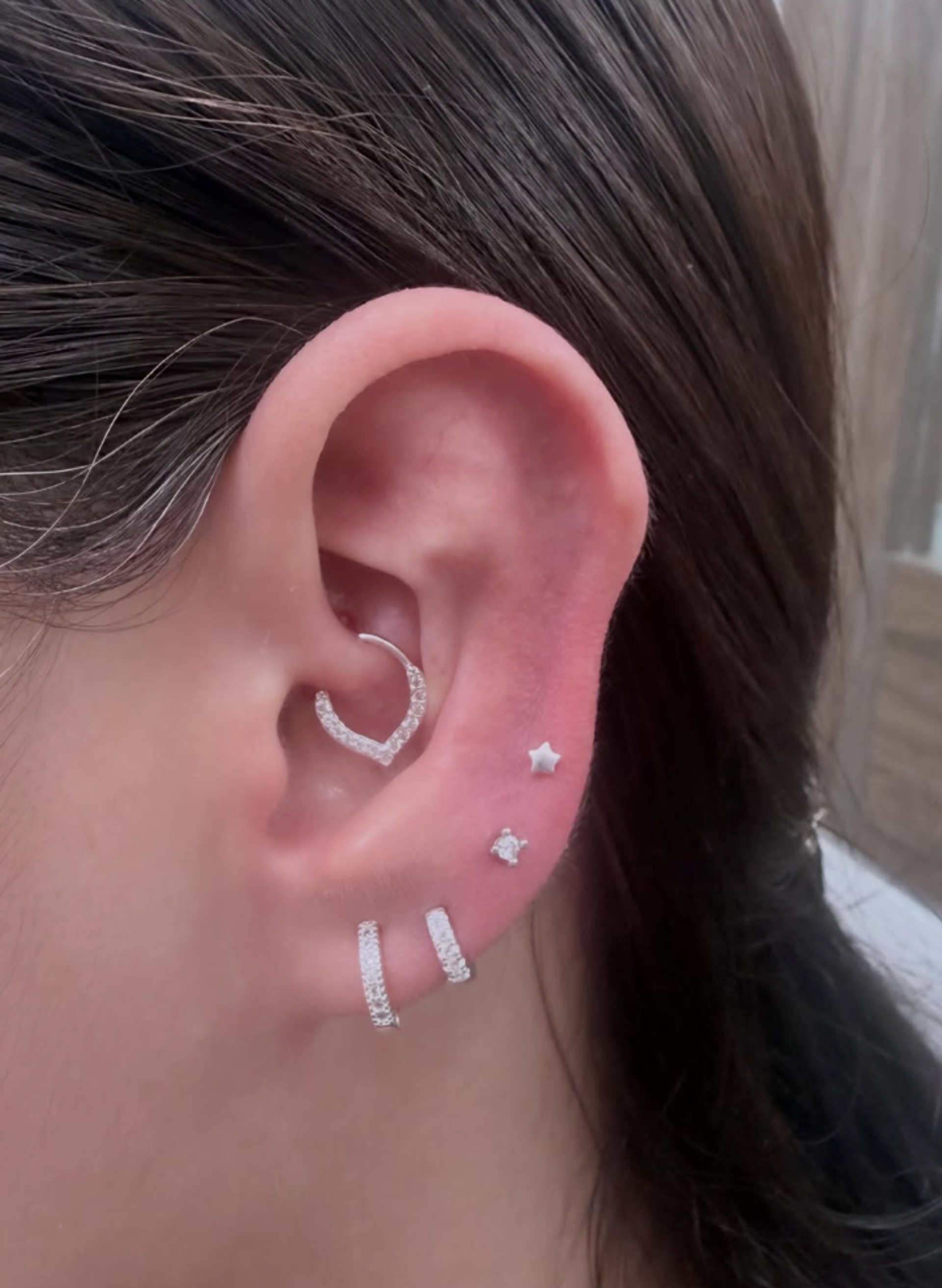 Perforación de oreja realizada con aros plateados