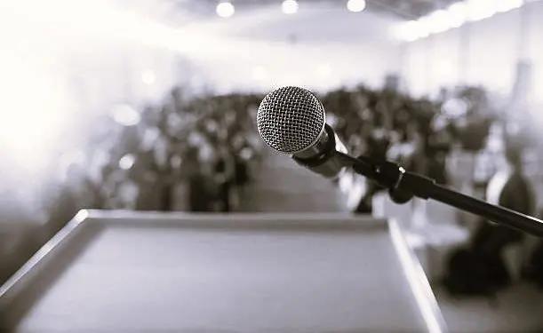 A microphone on a lectern in front of a blurred audience.