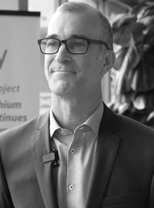 A company representative in front of a project banner at an investor event.
